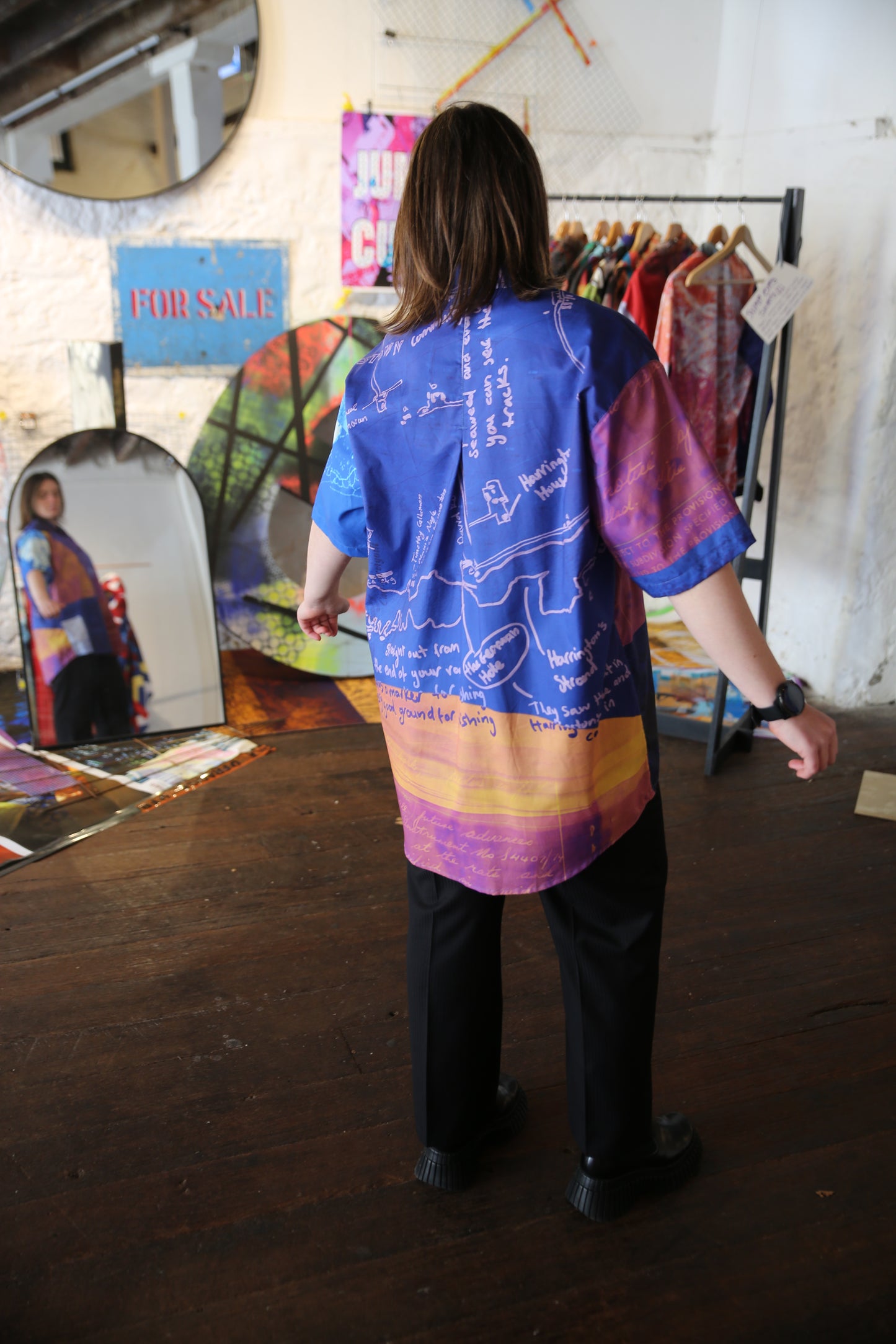 Person wearing a colorful printed shirt , standing in front of a mirror.