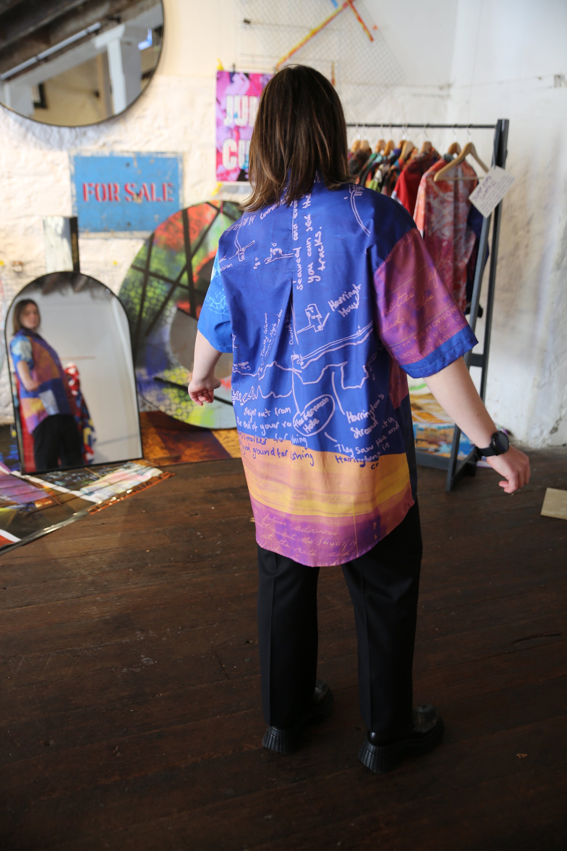 Person wearing a colorful printed shirt , standing in front of a mirror.