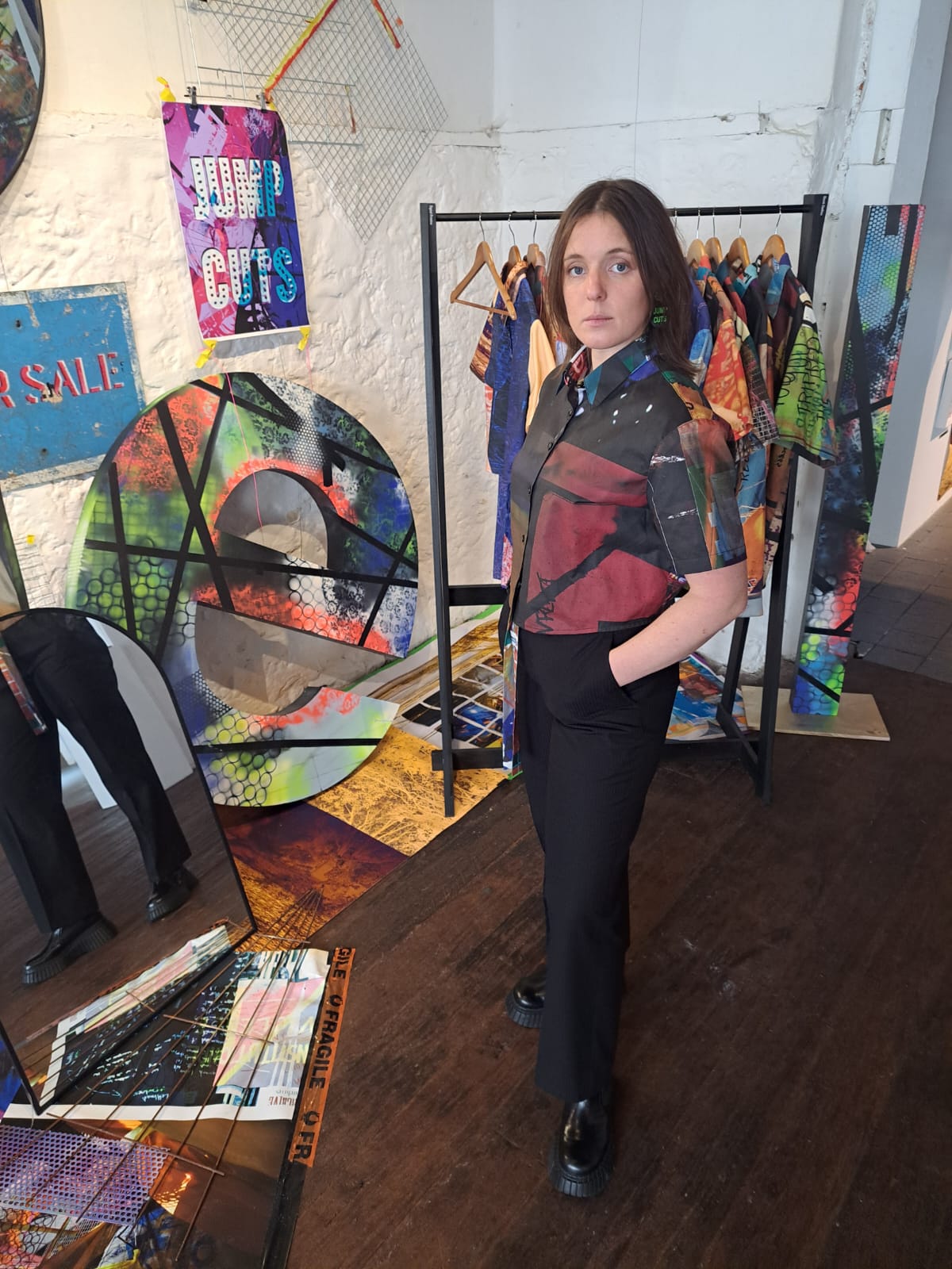 Woman standing in a room with art on the walls and floor.
