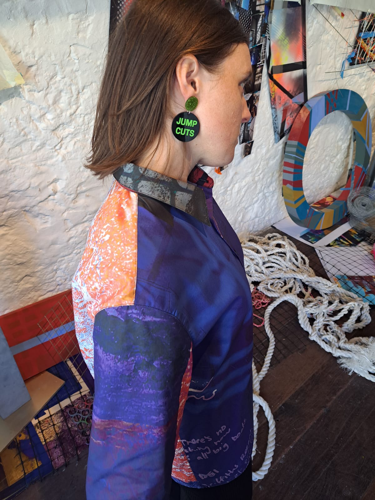 Person wearing colorful clothing with a textured wall and abstract art in the background